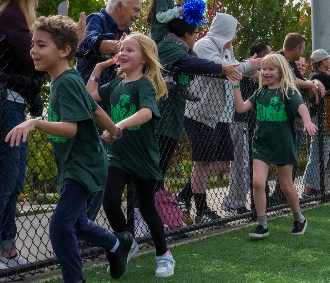 Students running past a fence line of cheering families